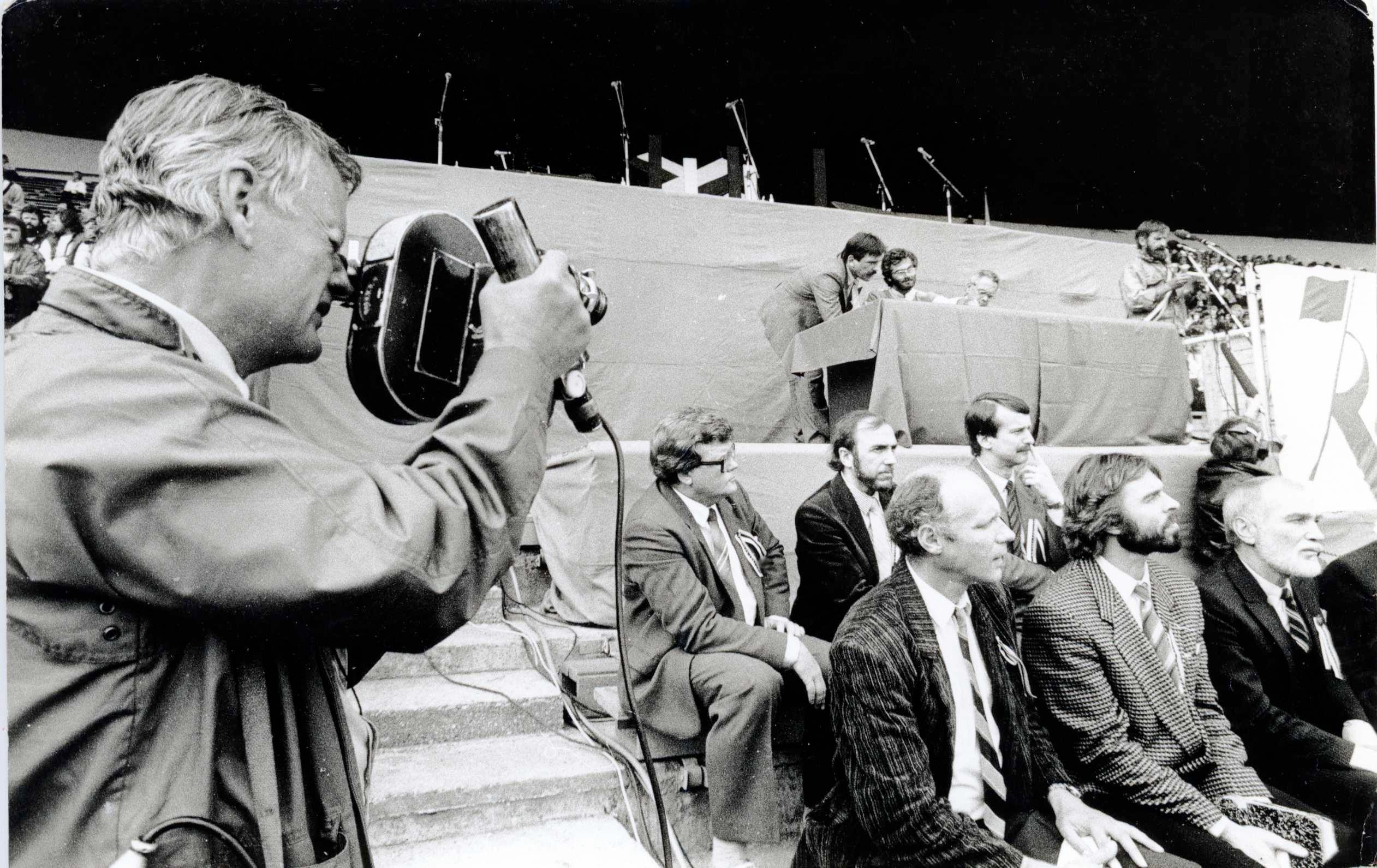 Filmivõtted Tallinna Lauluväljakul 11. septembril 1988. Kaameraga Andres Sööt. I reas istuvad: Raivo Trass, Martin Veinmann, Mikk Mikiver. II reas istuvad: Edgar Savisaar, Rein Veidemann, Siim Kallas. Laua taga istuvad Hagi Šein ja Rein Järlik. Kõnepuldis Heinz Valk