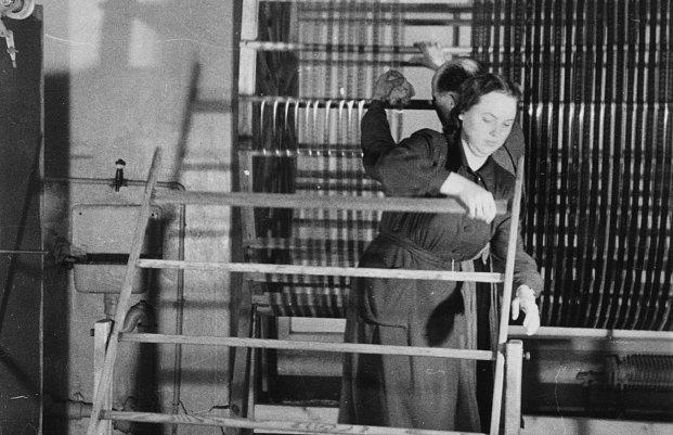 Filmi töötlemine filmilaboratooriumis, laborandid (Ellen Nigol) kerivad filmi raamilt trumlile. Kaader kinokroonikast „Päev Tallinna Kinostuudios“ (1950), Ringvaade „Nõukogude Eesti“ nr 4, 10. veebruar 1950, 3/4