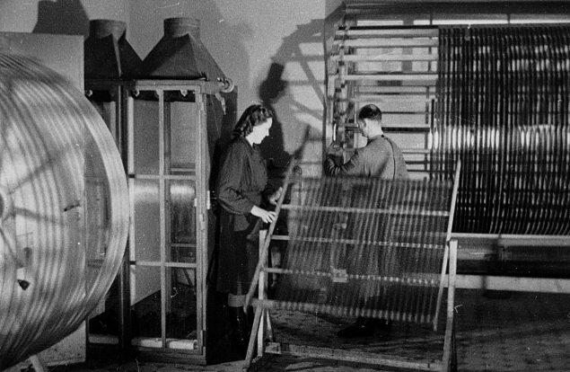 Filmi töötlemine Tallinna Kinostuudio filmilaboratooriumis, laborandid (Ellen Nigol) kerivad filmi raamilt trumlile. Kaader kinokroonikast „Päev Tallinna Kinostuudios“ (1950), Ringvaade „Nõukogude Eesti“ nr 4, 10. veebruar 1950, 3/4